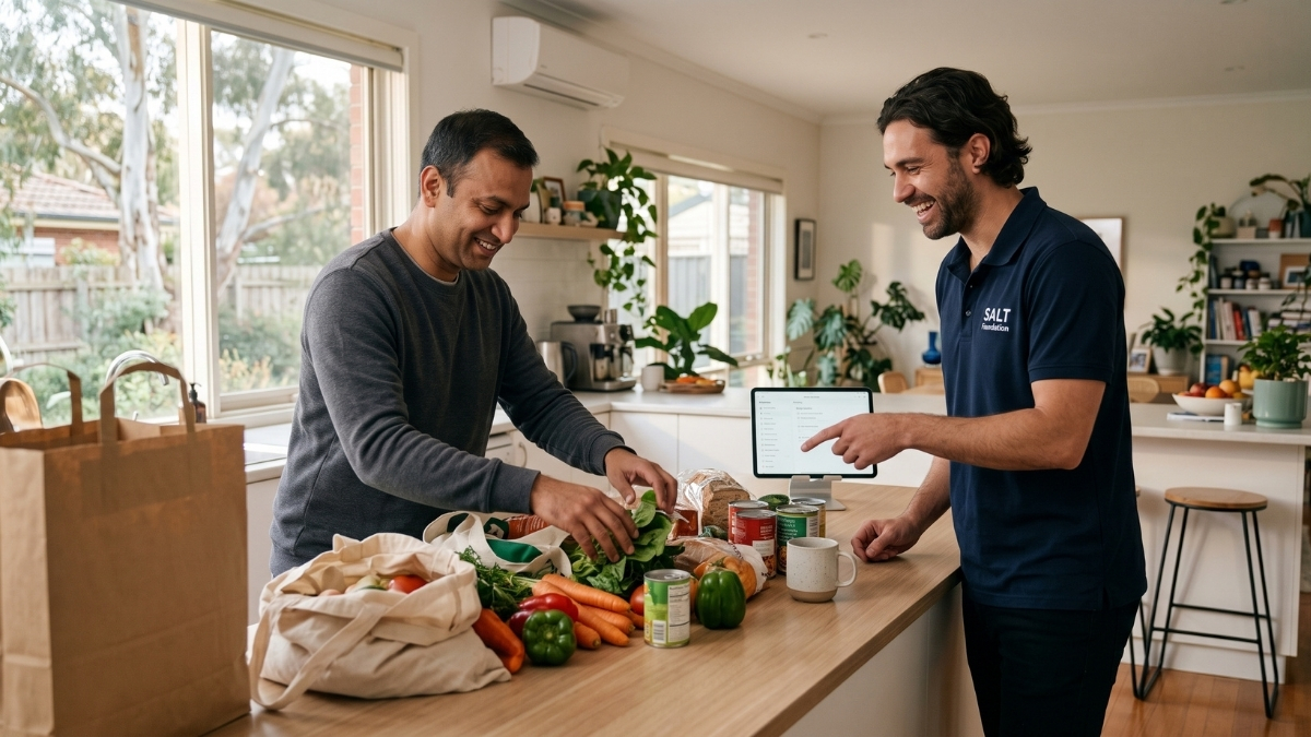 NDIS participant living with a mental health condition unpacking groceries with a support worker in his Melbourne kitchen.